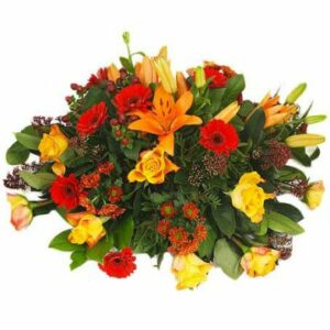 Låg rund begravningsdekoration med blandade blommor i rött, orange och gult tillsammans med gröna blad. En färgsprakande dekoration från Florister i Sverige.