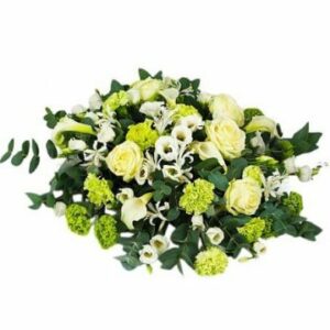 Låg rund begravningsdekoration med blandade blommor i vitt. Dekorationen finns att beställa hos Florister i Sverige.