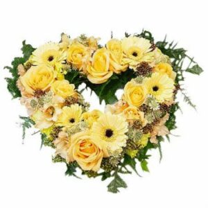 Begravningshjärta med blandade gula blommor och gröna blad. Du hittar hjärtat hos Florister i Sverige.