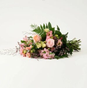 Liggande begravningsbukett med blommor i ljusa pastellfärger. Blommorna finns att beställa online hos Interflora.