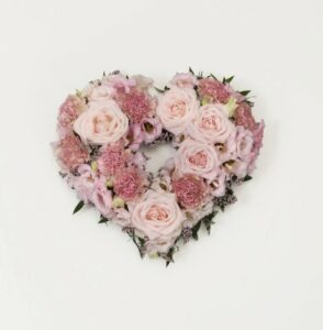 Öppet begravningshjärta med blandade blommor i olika rosa nyanser. Skicka med bud till begravningen via Interflora!